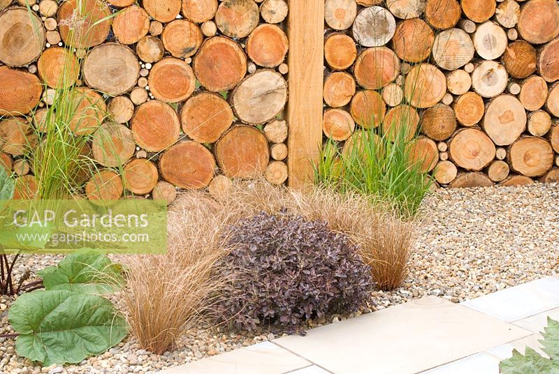 Mur en bois créé par un motif de rondins et de parterres de gravier. Carolyn R Hardern Garden Design