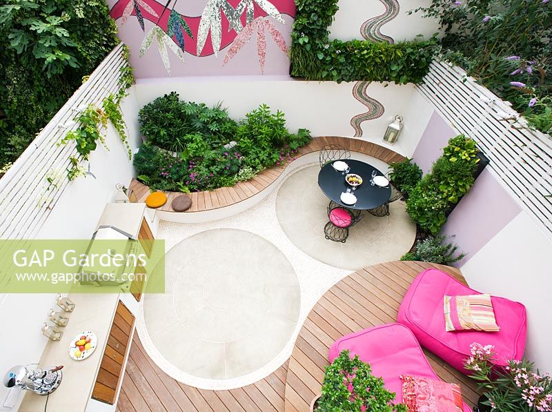 Portrait de petit jardin patio avec terrasse en bois, chaises roses, mosaïque par Celia Gregory, Londres.