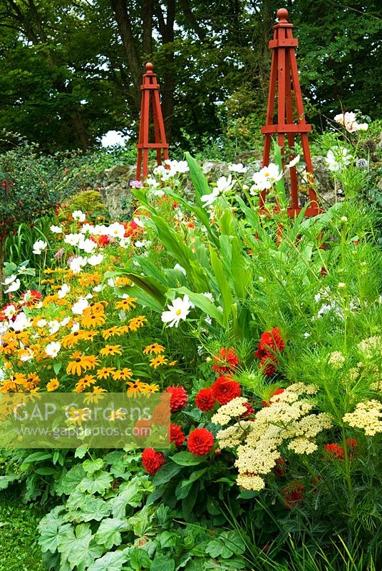 Parterre de fleurs décoratif ponctué d'obélisques en bois rouges