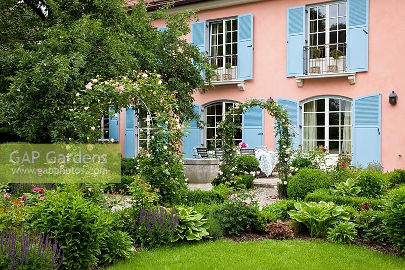 Maison aux volets bleus et jardin avec des arches de rose de Rosa 'Pierre de Ronsard' - Sac à main Garde, Freising, Allemagne