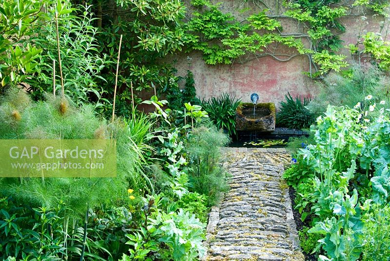 Le chemin de pierre mène à un petit plan d'eau entre les parterres de tithonie, de dahlia 'David Howard', de fenouil en bronze et de Salvias. Dorset, Royaume-Uni