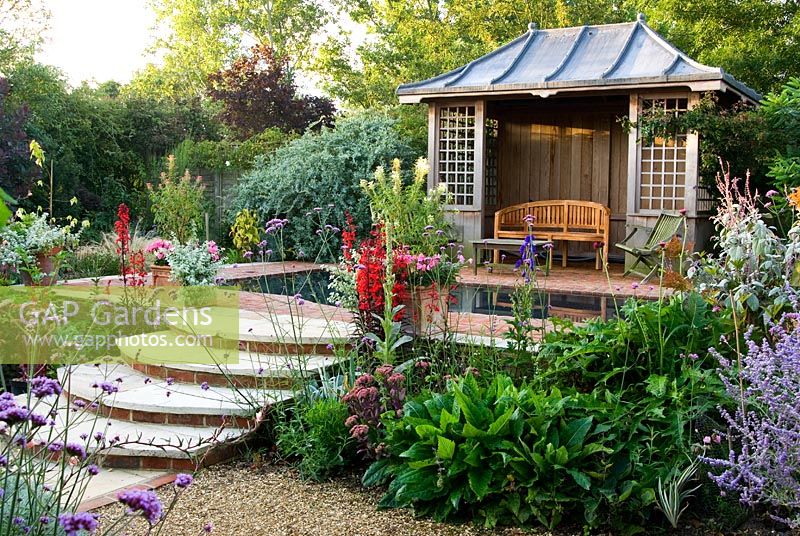 Maison d'été avec piscine réfléchissante entourée de vivaces aux couleurs vives, y compris Lobelia cardinalis, Cleomes, Plectranthus et Aconites - Isle of Wight, Royaume-Uni