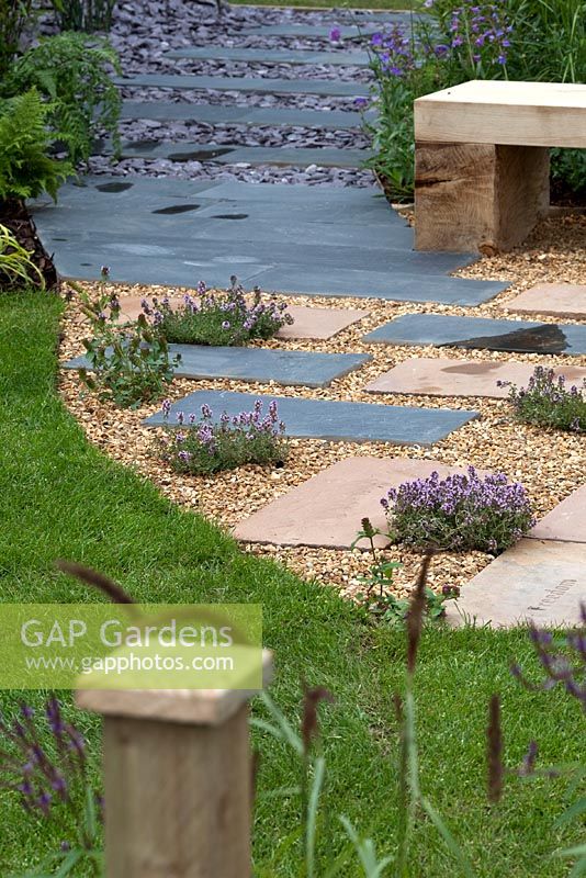 Chemin en ardoise, pierre et gravier à travers un jardin moderne