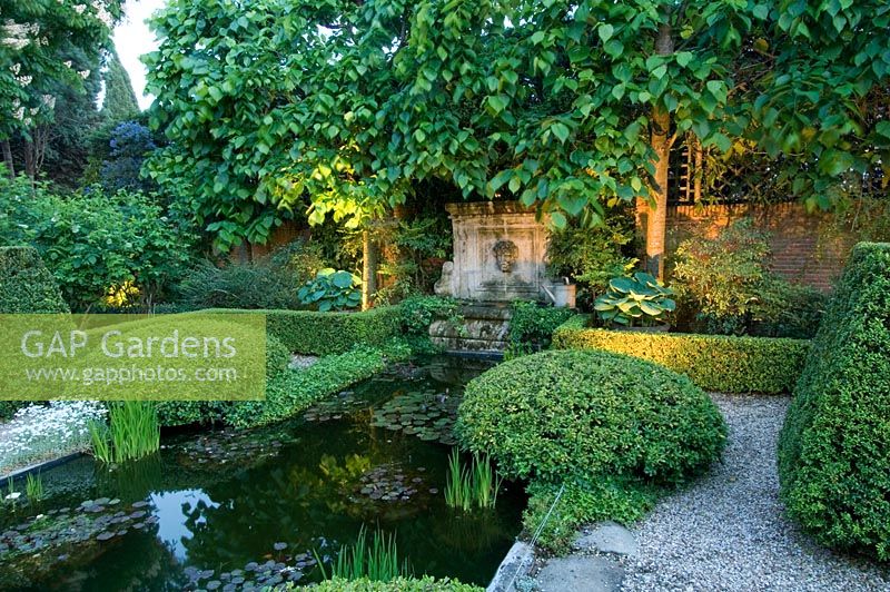 Jardin méditerranéen de style formel avec haie basse entourant l'étang, le topiaire, l'éclairage, les chemins de gravier et les limes blanchies - Madrid, Espagne