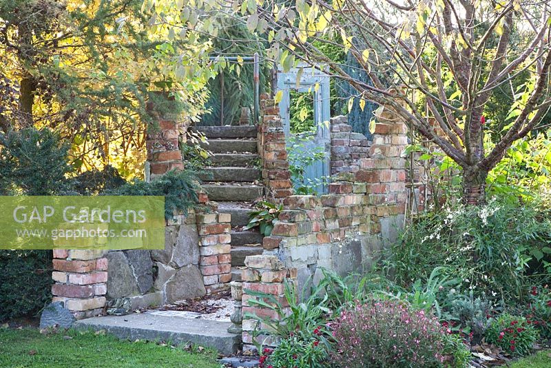Restes de mur en ruine et porte recyclée dans le jardin