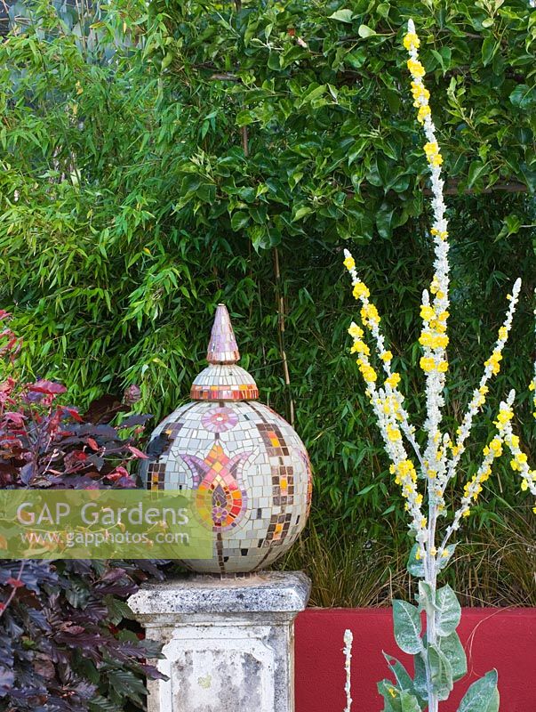 Sphère en mosaïque avec motif de tulipes turques sur socle en pierre entouré de verbascums