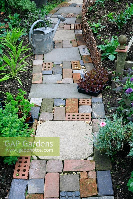 Chemin de style jardin de chalet fait de matériaux récupérés, y compris des dalles, des briques, des pavés en blocs de béton et des cailloux