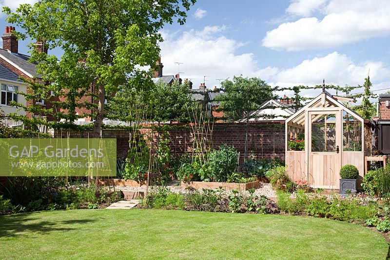Étape par étape - Vue d'ensemble du jardin avec serre, bordure végétale surélevée et charmes blanchis