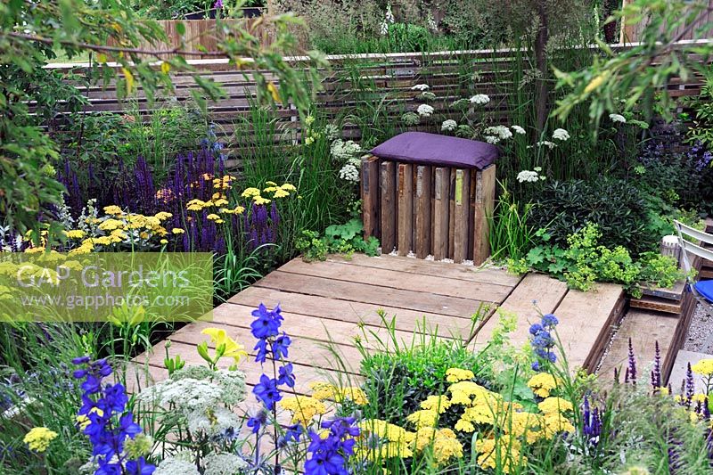 Plantation bleue et jaune autour de la terrasse en bois avec un siège inhabituel - Notre première maison Notre premier jardin, Hampton Court Palace flower show 2012