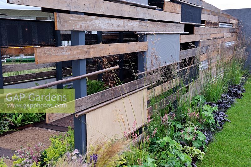 Graminées et vivaces le long de la clôture construites à partir de matériaux récupérés. 'La lumière au bout du tunnel', Hampton Court Palace Flower Show 2012