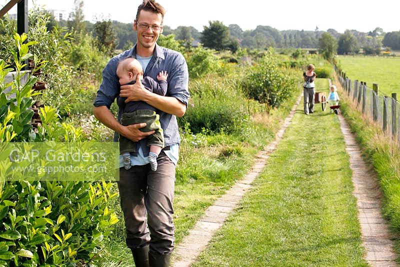 Martin Heutink et sa femme Margriet avec leurs deux enfants Nina et Sven marchant sur le chemin dans le jardin sauvage - Nursery Bloemrijk