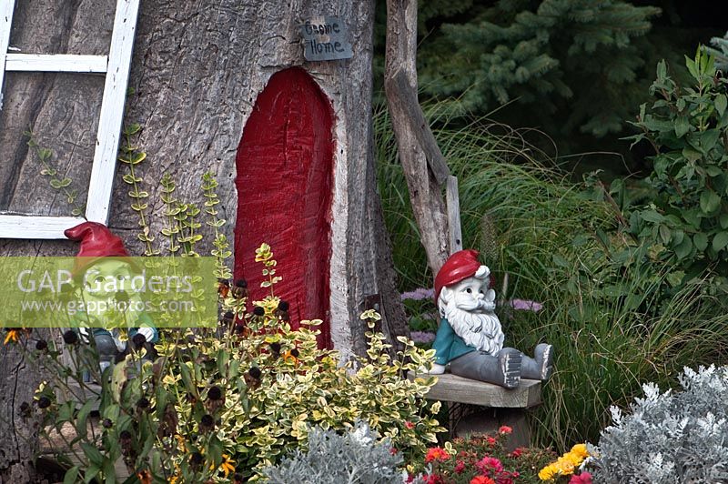 Accueil Gnome à base de tronc d'arbre, plantation d'Euonymus, Senecio cineraria, Rudbeckia, Portulaca et Sedum