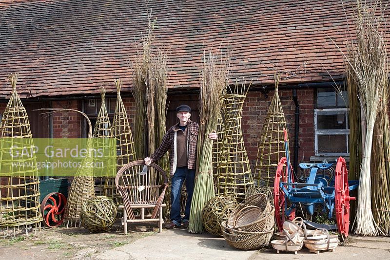 Le tisserand de saule Dominic Parrette avec une variété de ses créations, des supports de plantes, une sphère sculpturale, une chaise gitane, des trugs et des paniers - Sussex Willow