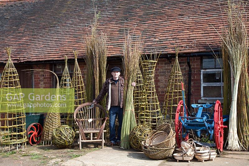 Le tisserand de saule Dominic Parrette avec une variété de ses créations, des supports de plantes, une sphère sculpturale, une chaise gitane, des trugs et des paniers - Sussex Willow