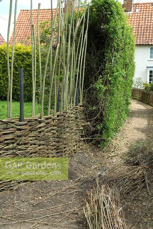 Construction d'une clôture en saule - Clôture prise au coin du jardin pour répondre à la haie de conifères existante