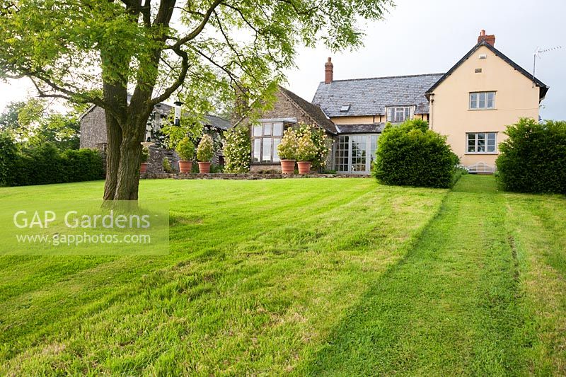 La maison est située sur un site plat au sommet d'une longue pelouse en pente, offrant une vue sur la campagne environnante. Ashley Farm, Stansbatch, Herefordshire, Royaume-Uni
