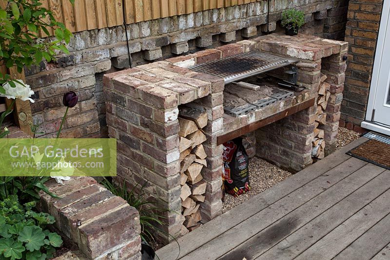 Barbecue avec bûches coupées sur un patio en bois