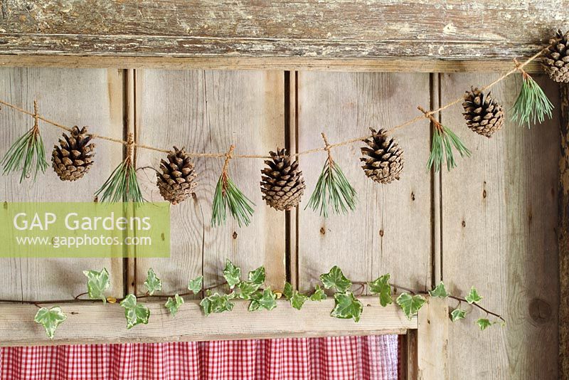 Étape par étape de faire une guirlande de Noël simple et rustique avec des pommes de pin et des aiguilles de pin - La guirlande finie accrochée à une porte en bois