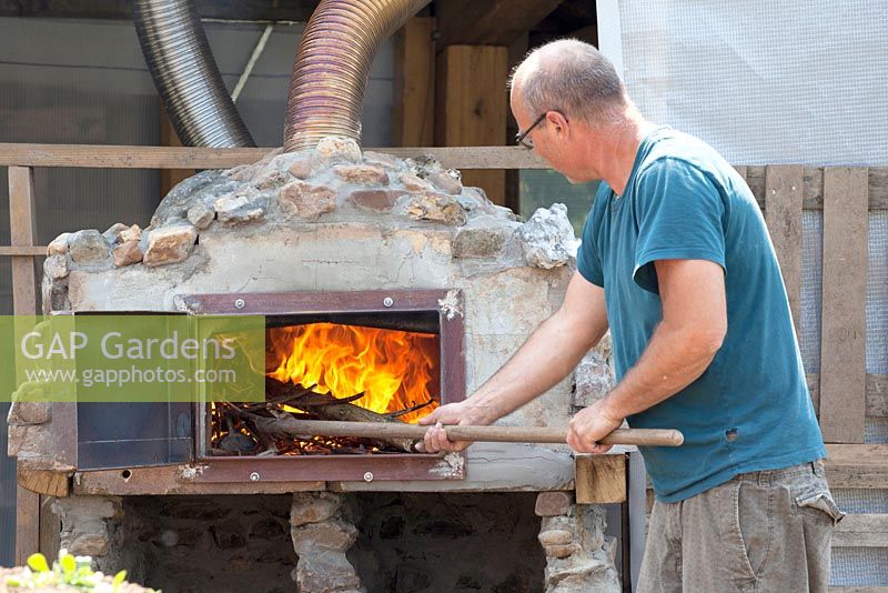 Préparer le four à pizza en brûlant du bois.