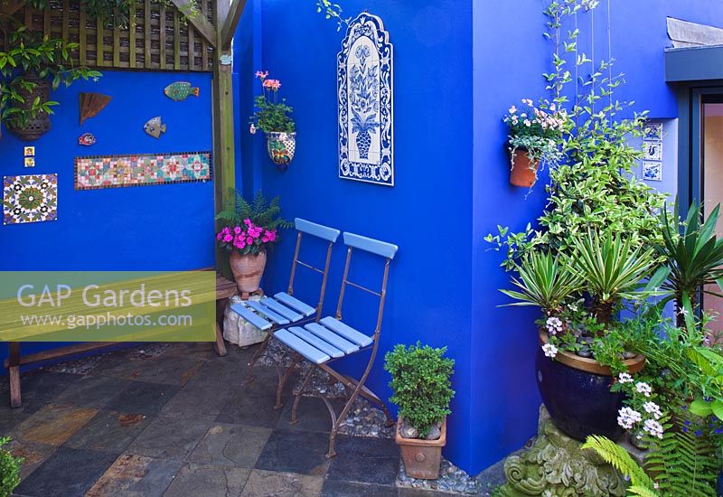 Petit jardin de ville - Cour avec murs bleu cobalt, chaises de café bleues et sol en ardoise.