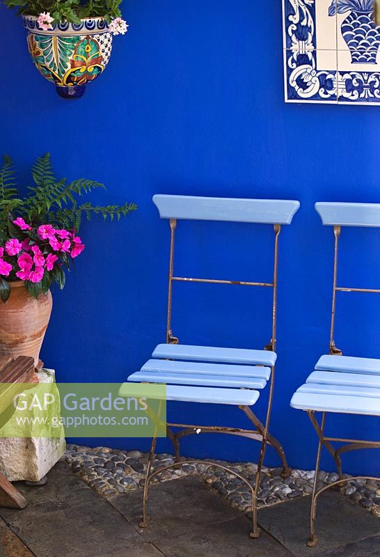 Petit jardin de ville - Cour avec murs bleu cobalt, chaises de café bleues et tableau en céramique du Portugal, pot en céramique et pot en terre cuite.