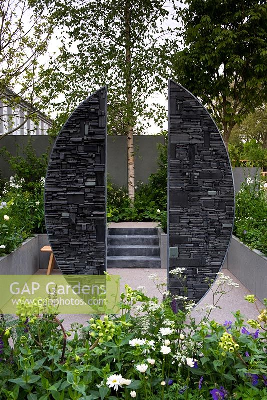 Sculpture en ardoise de Tom Stogdon dans un jardin en contrebas avec des bordures environnantes