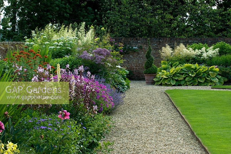 Jardin d'été avec parterres de fleurs, chemin de gravier et pelouse. Tour de Kirtling, Suffolk
