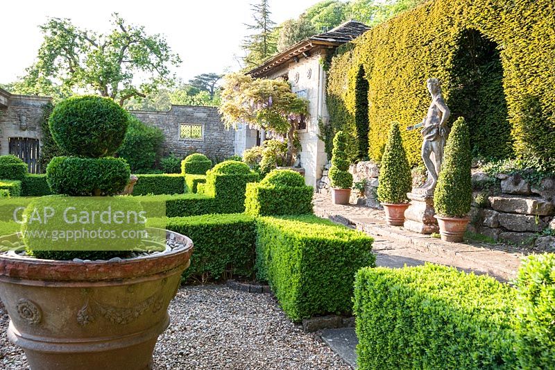 Coffret parterre avec Casita au-delà et statue de jeunesse italienne en marbre contre la haie d'ifs.