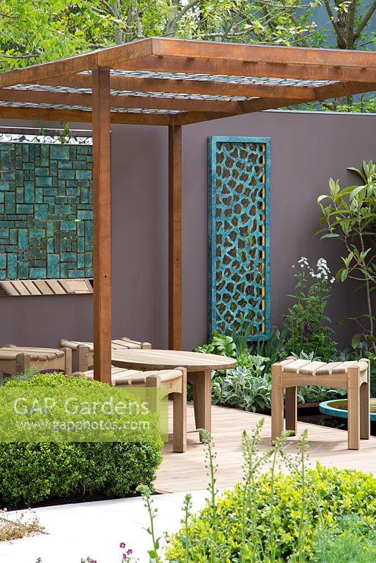 Coin salon de jardin avec des sculptures de David Harber. Pergola en acier corten.