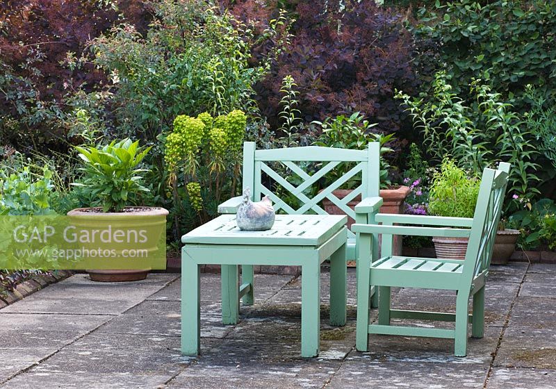 Banc et chaises en bois peint en vert sur terrasse. Sandhill Farm House, Hampshire