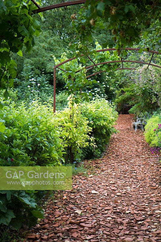Chemin de jardin avec surface de pots en terre cuite cassés. Promenade sous pergola aux Jardins des Paradis à Cordes sur Ciel, France