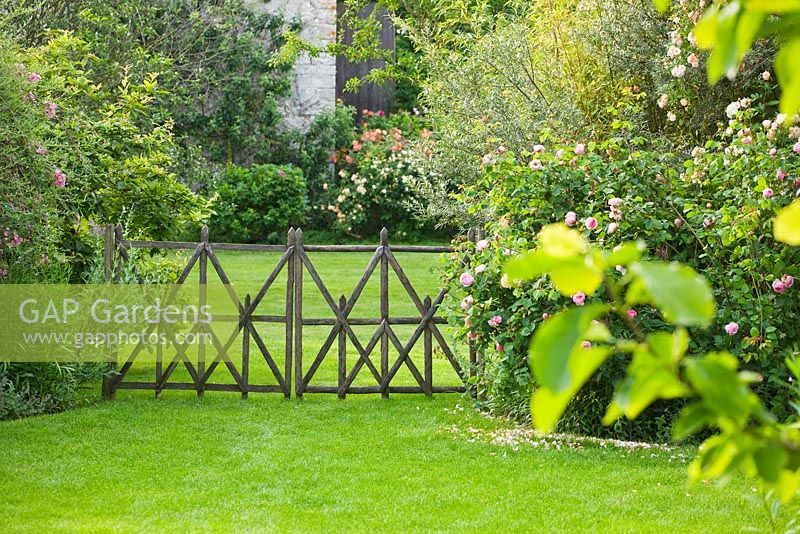 Pelouse et clôture décorative en bois par Stéphane Cassine. Les Jardins de Roquelin, Vallée de la Loire, France