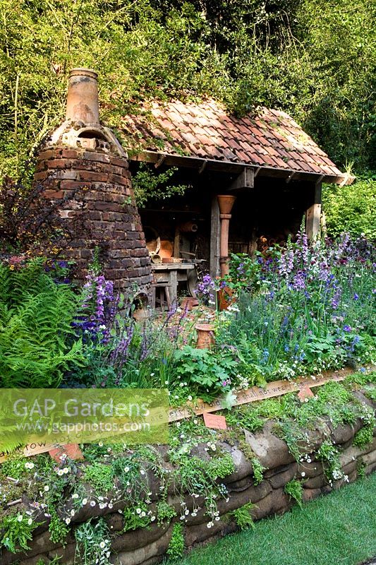 Potter's Garden Kiln, Sandbag wall and cottage planting flowerbed shadow. Composez un vol, RHS Chelsea Flower Show 2014.
