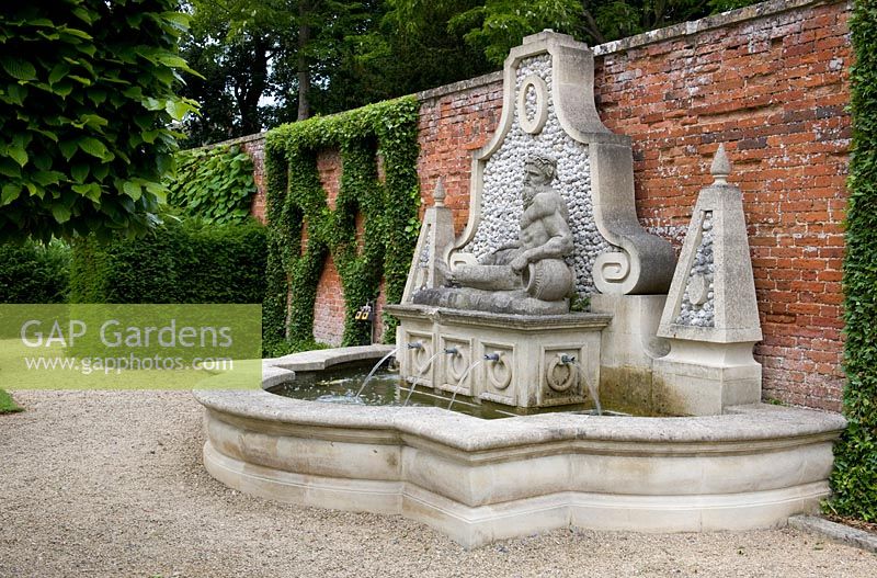 Grande pièce d'eau classique en pierre avec plusieurs jets d'eau, représentant peut-être Neptune, dans un jardin clos - Seend, Wiltshire