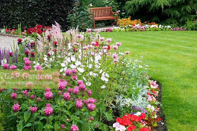 Parterre herbacé d'été avec Sidalcea 'Elsie Heugh' Monarda 'Croftway Pink' Monarda 'Pink Lace' et annuelles avec pelouse et coin salon au-delà