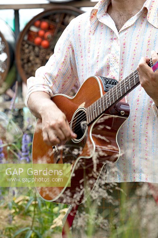 Or. Meilleur jardin d'été. Un espace pour se connecter et se développer. Conception: Jeni Cairns et Sophie Antonelli. Interprète avec guitare chantant une chanson dans le jardin.