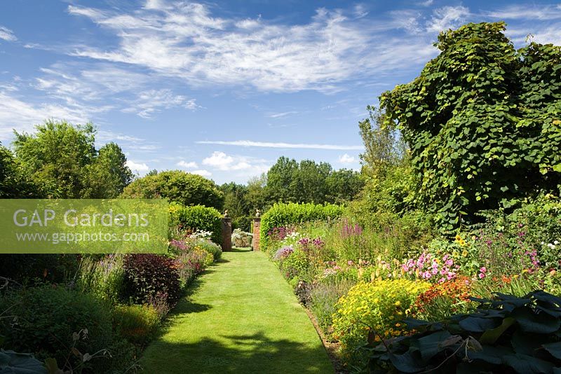 Les parterres de fleurs herbacées doubles à la recherche de la maison. Hall Farm Garden à Harpswell près de Gainsborough dans le Lincolnshire. Juillet 2014.