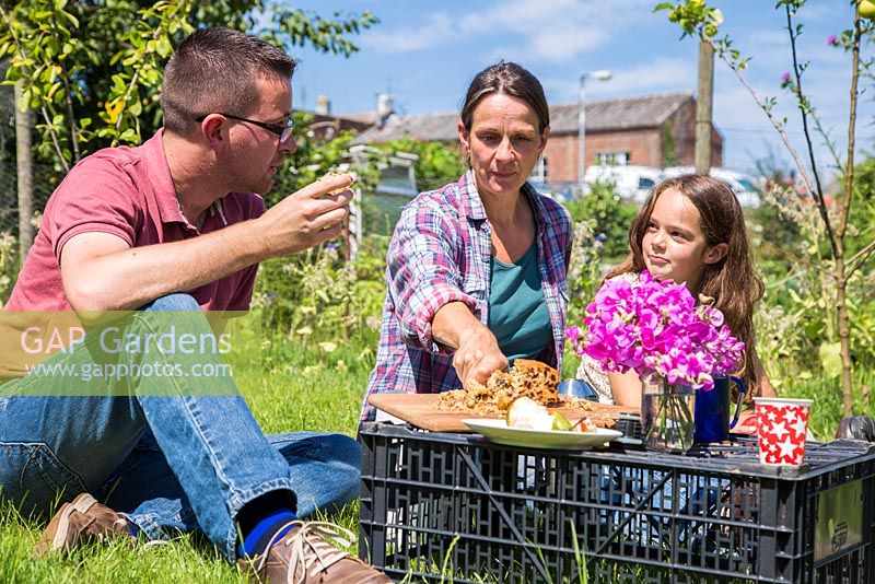 Famille en train de manger un pique-nique dans un lotissement