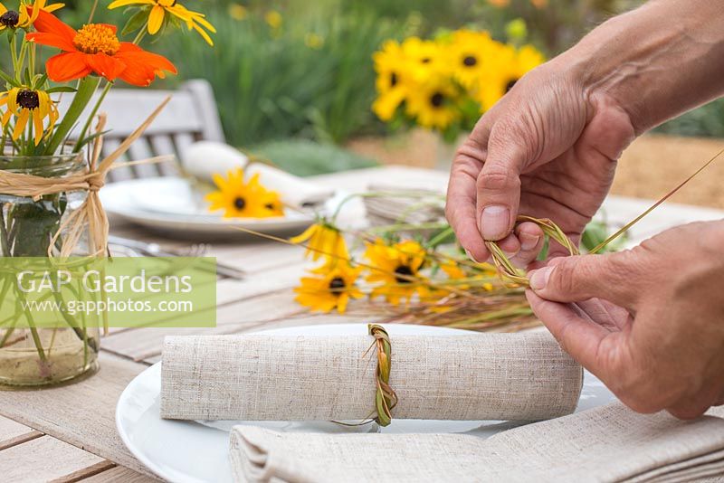 Femme créant des décorations de table à l'aide de rudbeckia, tithonia et stipa gigantea grass