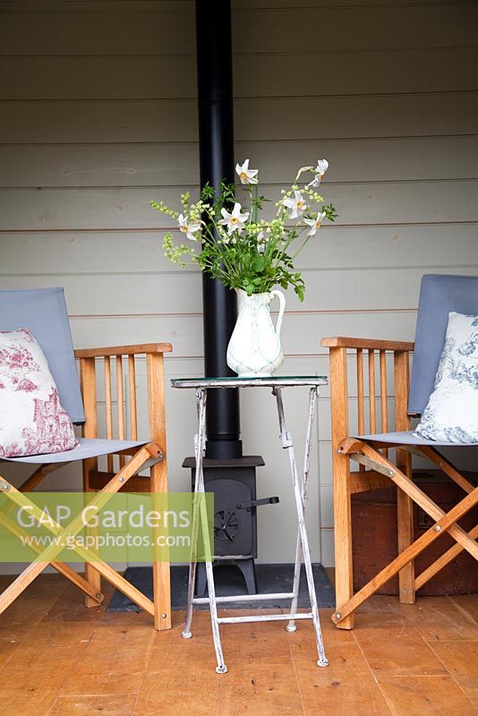 Chaises en bois et poêle à bois dans Shepherds Hut avec des fleurs de printemps en pot