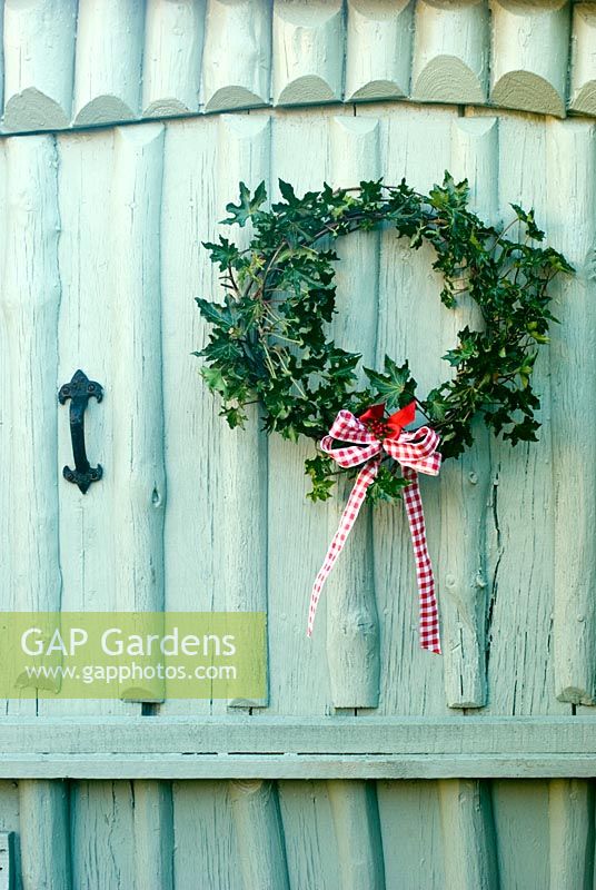 Décorations de Noël de votre jardin - couronne faite de branches choisies de conifères et de capitules suspendus à une porte peinte