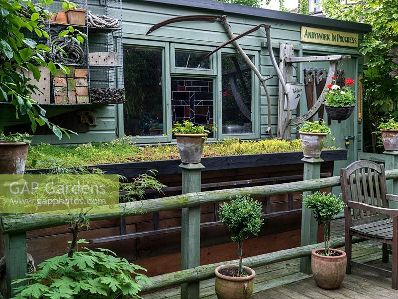Un abri de jardin et une unité de stockage avec toit vert. Le propriétaire, Andy Hutchings, avait un panneau spécialement conçu pour la porte ci-dessus 'Andywork in Progress' parce que c'est son atelier.