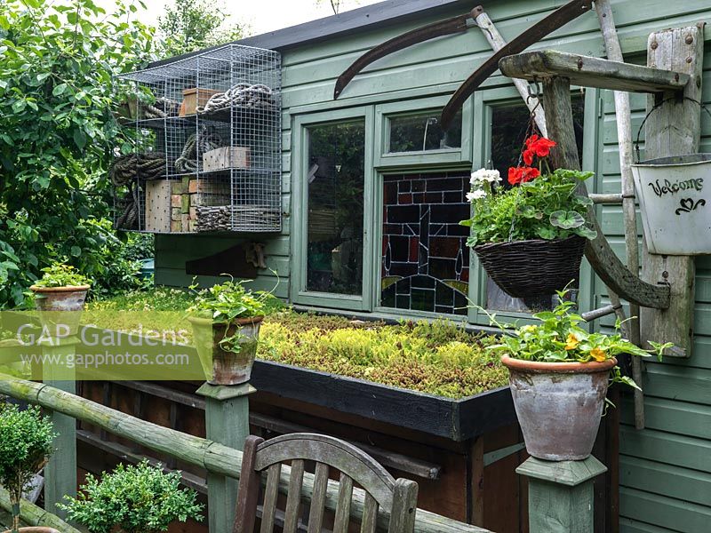 Un abri de jardin et une unité de stockage avec toit vert.
