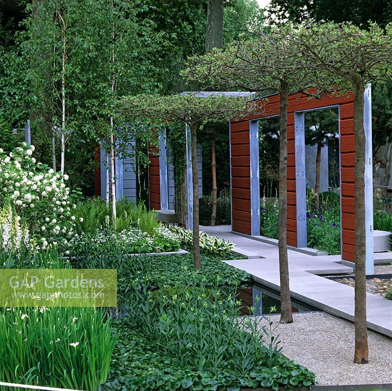 Des paravents en bois rouge et gris divisent le jardin moderne. Passerelle de granit passe des piscines et des parterres d'iris, de lys martagon, de fougère, d'hosta, de digitale, de bouleau.