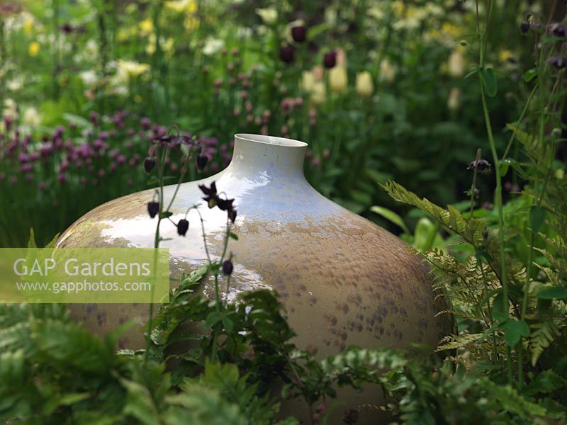 Reposant dans un parterre de fleurs herbacées, joli pot à glaçure cristalline par le potier John Stroomer.
