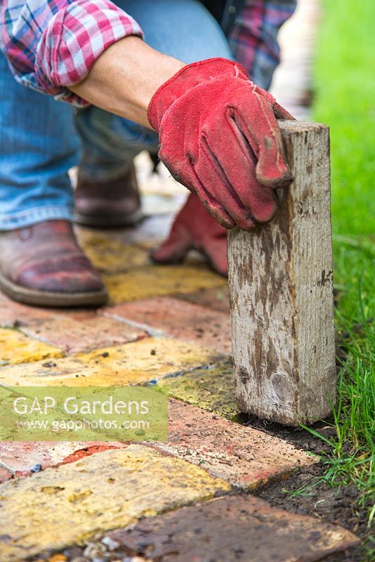 Utiliser un morceau de bois carré pour comprimer le sol dans les interstices.