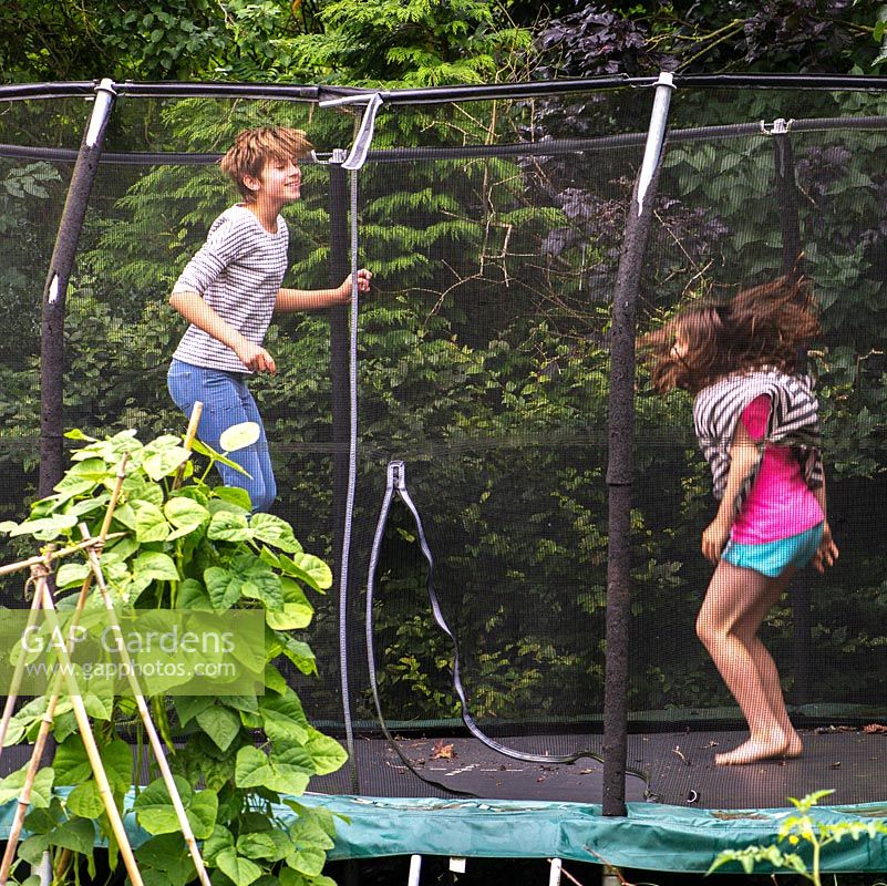 Lily, 10 ans, et Scarlett, 13 ans, jouent sur le trampoline niché au fond du jardin.