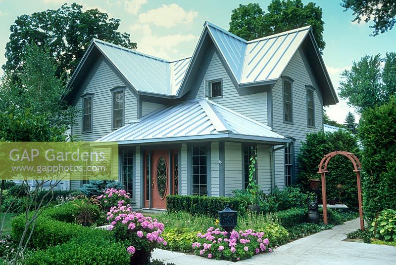 Maison américaine du 19ème siècle avec haie de buis, arc en bois, pélargoniums. Milford, Michigan, États-Unis