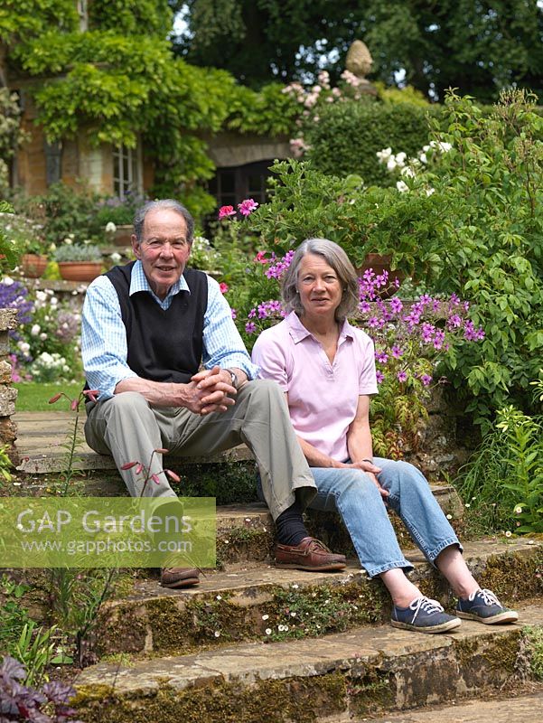 Iain et Susie Pasley-Tyler sur les marches sous leur terrasse bordées de valériane, de géranium rustique, de lis et de pélargonium.