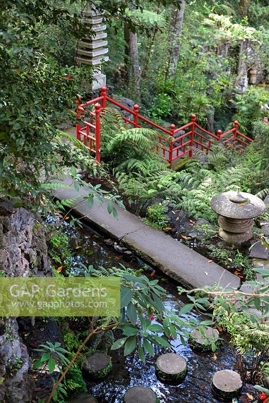 Pont de pierre traversant l'étang avec des pierres de gué rondes au jardin tropical de Monte Palace, Madère, dans le jardin oriental, avec des objets japonais et des balustrades rouge vif